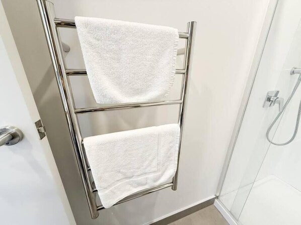 A bathroom with a chrome towel rack holding two white towels. - Central Haven Studio on Queen Street  (Auckland)