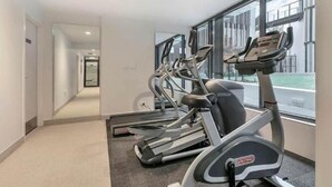 A gym with treadmills and a hallway leading to another room. - Central Haven Studio on Queen Street  (Auckland)