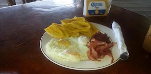 Savor a hearty breakfast with eggs, bacon, and plantain chips, paired with a cold beer.