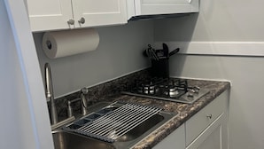 A kitchen with white cabinets, a stainless steel sink, a microwave, and a gas stove. - Historic Downtown 1BR 2 Queens Near WVU & Dining (Morgantown)