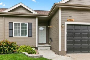 A residential house with a garage, a front door, and a mailbox.