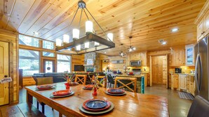 Un intérieur en bois comprenant une table à manger pour quatre personnes, un coin cuisine et un espace de vie avec un canapé.