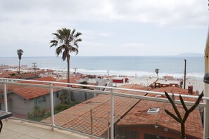 Un barrio residencial con techos de tejas rojas, una palmera y vistas a la playa y el océano.