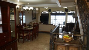 A spacious living area with a dining table, chairs, a sofa, and a staircase with a fruit bowl on the landing. - Beautiful Ocean View Home In San Antonio del Mar (Tijuana)