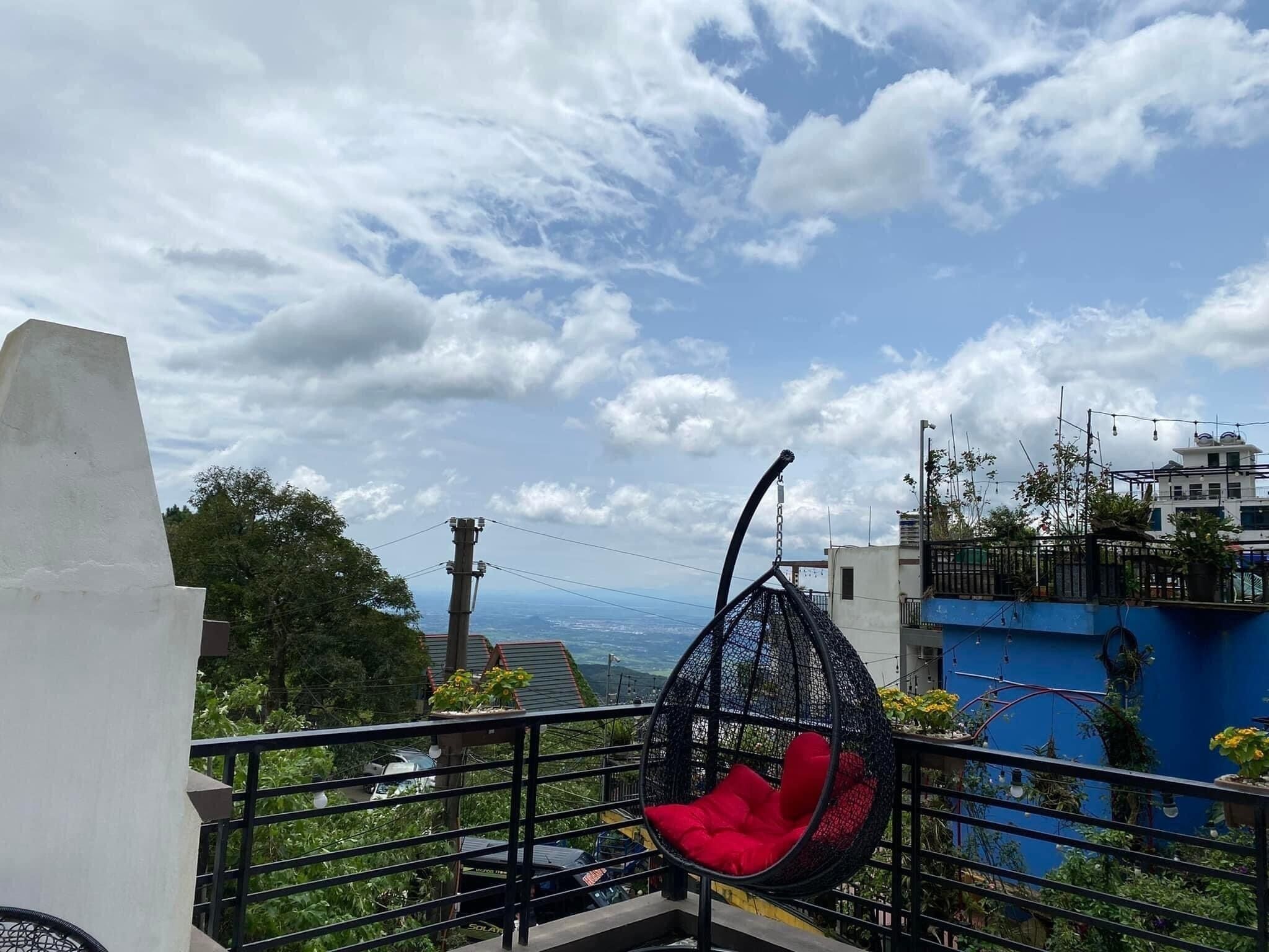 Un balcón con una silla colgante y vistas a la ciudad, además de una barandilla.