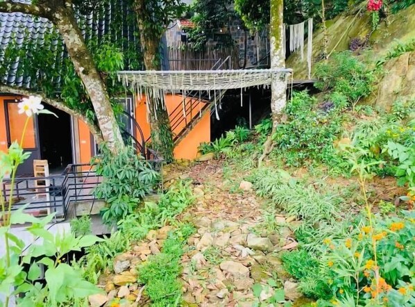 A garden area with a hammock, stone pathway, and various plants.