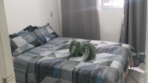 A bedroom with a bed, grey curtains, a window, and a radiator. - Fairs and Shopping 202 (Vila Maria Alta São Paulo)