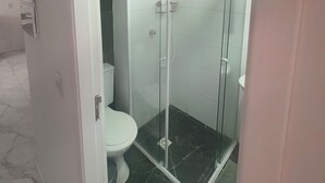 A bathroom with a glass-enclosed shower, a toilet, and a marble floor. - Fairs and Shopping 202 (Vila Maria Alta São Paulo)