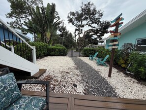 A patio area with a gravel ground, outdoor furniture, and a directional signpost.