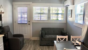 A compact living space with a sofa, two chairs, a small table, and a door with windows.
