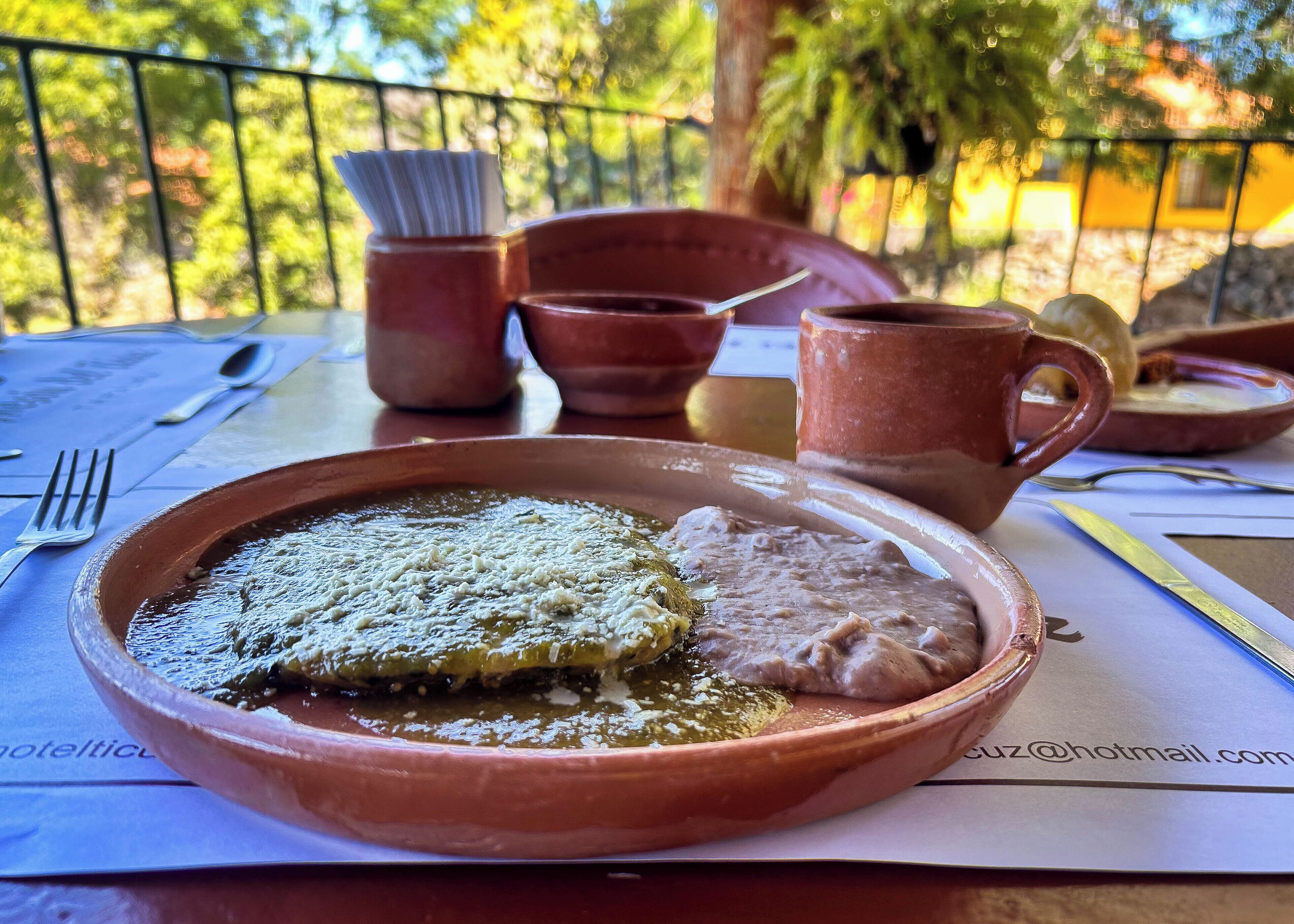 A meal on a table with a plate, a cup, and a spoon.