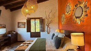 A cozy bedroom with a bed, a nightstand, a lamp, and a wall-mounted mirror. - El Mesón del Ticúz Tapalpa (Tapalpa)