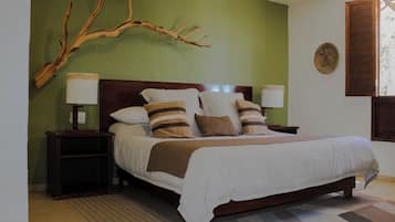 Een opgemaakt bed met een bruin-wit gestreept kussen, een houten hoofdbord en een groene muur.