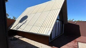 Un bâtiment moderne doté d’un toit métallique incliné et d’une grande fenêtre en verre.