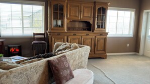 A living room with a fireplace, a large wooden cabinet, a sofa, and a bench. - Cozy farmhouse in charming Great Falls with WiFi, AC and indoor parking (Great Falls)