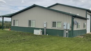 A two-story industrial building with a green and gray exterior, large windows, and outdoor electrical equipment. - Cozy farmhouse in charming Great Falls with WiFi, AC and indoor parking (Great Falls)