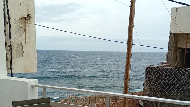 A table set for two on a balcony with a view of the sea.