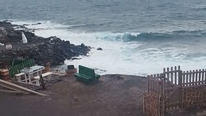 A beach with a rocky shoreline, a wooden fence, and a few benches.