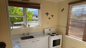 Eine kleine Küche mit einem weißen Herd, einem Spülbecken und einem Fenster mit Jalousien.