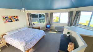 Un dormitorio con cama, escritorio, silla y vista al mar.