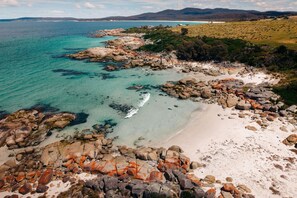 Un paisaje costero con costa rocosa, agua turquesa cristalina y una playa de arena.