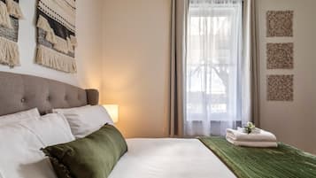 Ein Hotelzimmer mit Bett, Lampe, Fenster mit Vorhängen und dekorativer Wandgestaltung.