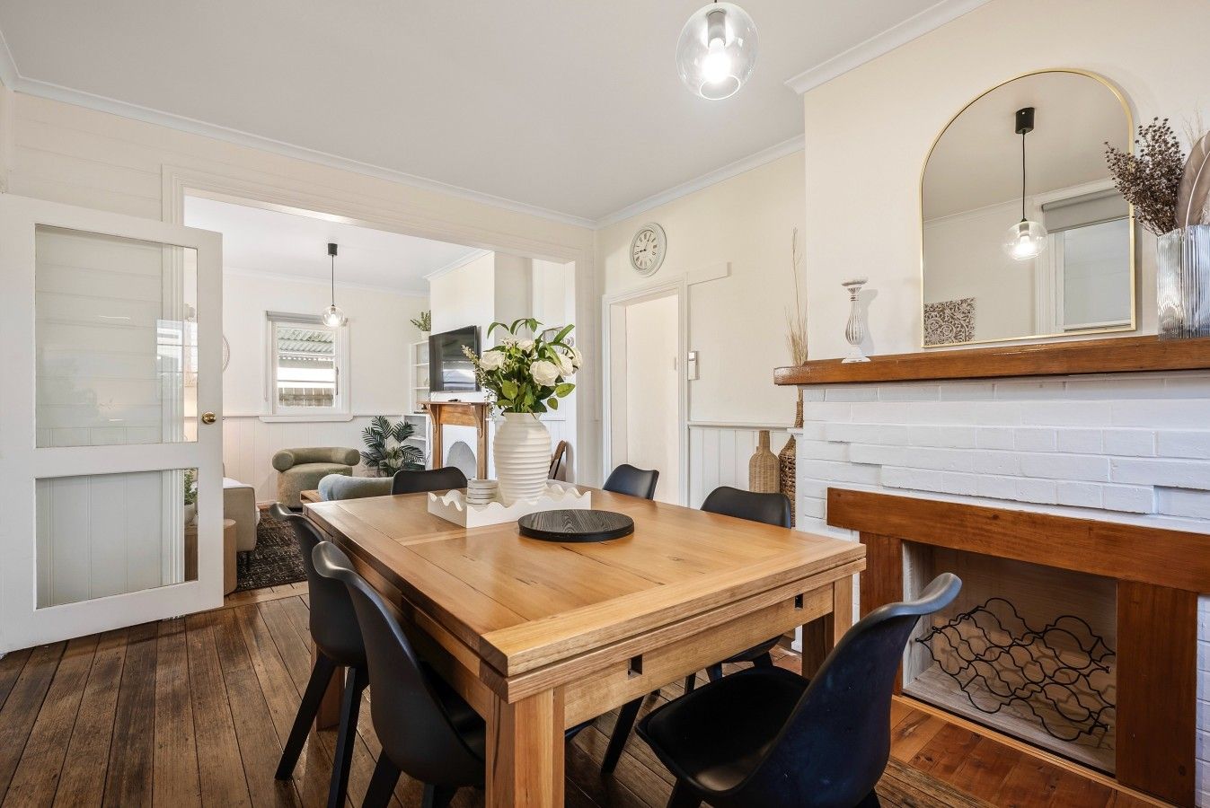 A dining area with a wooden table, chairs, and a vase of flowers.