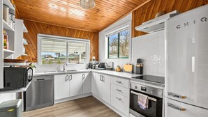 A modern kitchen with white cabinets, stainless steel appliances, and wooden ceiling.