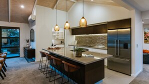 A modern kitchen with a large island, stainless steel appliances, and pendant lighting. - The Clearview House - Lake Views (Wanaka)