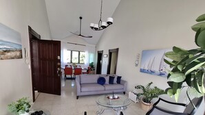 A modern living room with a sofa, coffee table, and chairs. There is a dining area in the background with a table and chairs. - Spacious 2BR, Fast WiFi/Ocean & Mountain Views, Security & Convenience (Puerto Plata)