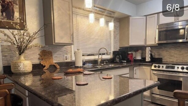 A kitchen with a central island, stainless steel appliances, and a window with blinds. - Anchors Way Inn (Anchorage)