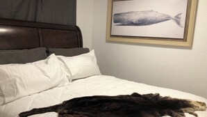 A bed with white bedding and a large, dark-colored cat lying on it. - Anchors Way Inn (Anchorage)