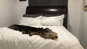 A bed with a white duvet, a dark brown headboard, and a large, dark brown fur throw. - Anchors Way Inn (Anchorage)