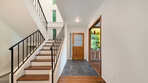 Una escalera con barandas negras que lleva a un rellano con una puerta y un estante con objetos de colores.