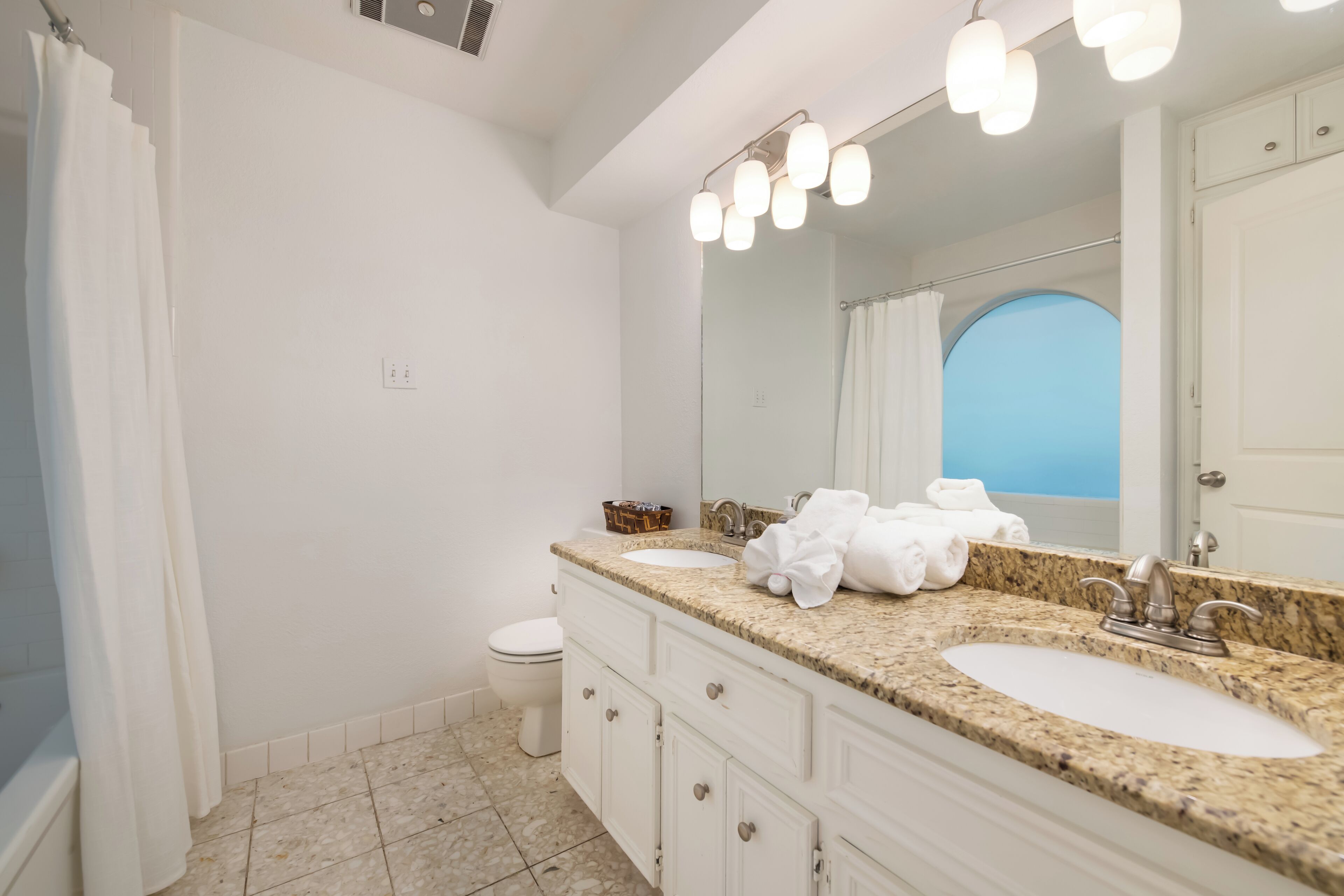 Une salle de bain avec deux lavabos, des toilettes et un rideau de douche.