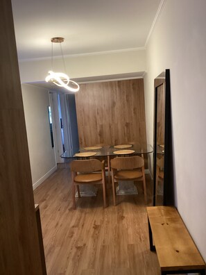 Ein Essbereich mit Glastisch, Holzstühlen und einer modernen Pendelleuchte.