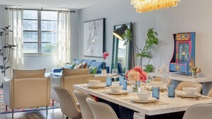 A dining area with a table set for four, a chandelier, and a view of the city through large windows.