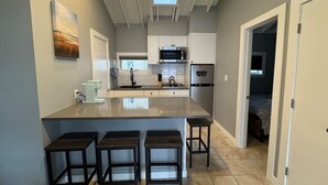 Una cocina moderna con una isla grande, taburetes de bar, un microondas y un lavabo.