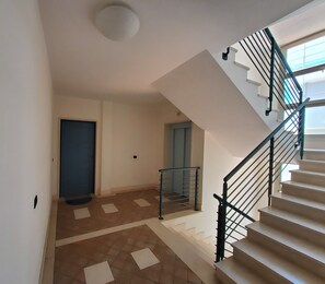 A staircase with a metal railing, a door, and a tiled floor.