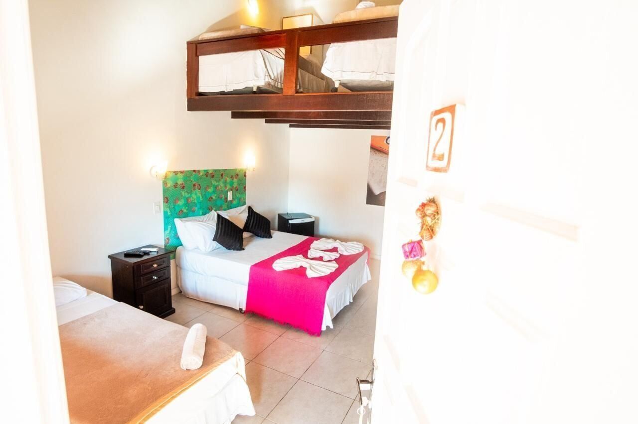 Un dormitorio con una cama litera, una mesita de noche y una cama con una manta rosa.