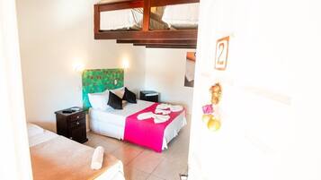 Un dormitorio con una cama litera, una mesita de noche y una cama con una manta rosa.