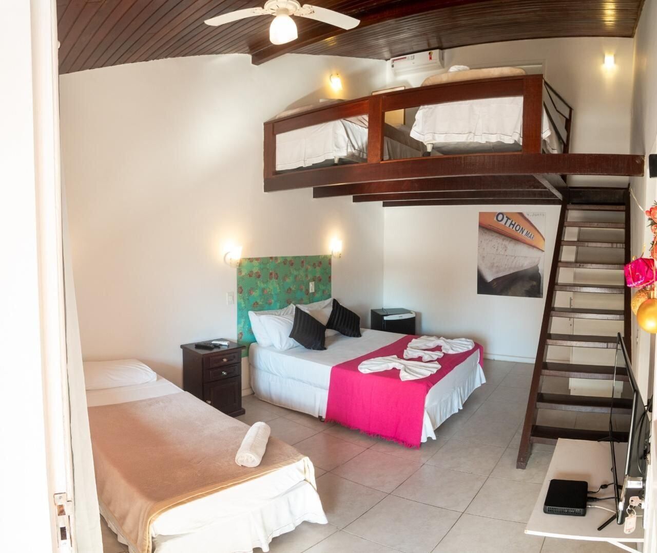 A room with a bunk bed, a single bed, a desk with a chair, a ladder, and a staircase.