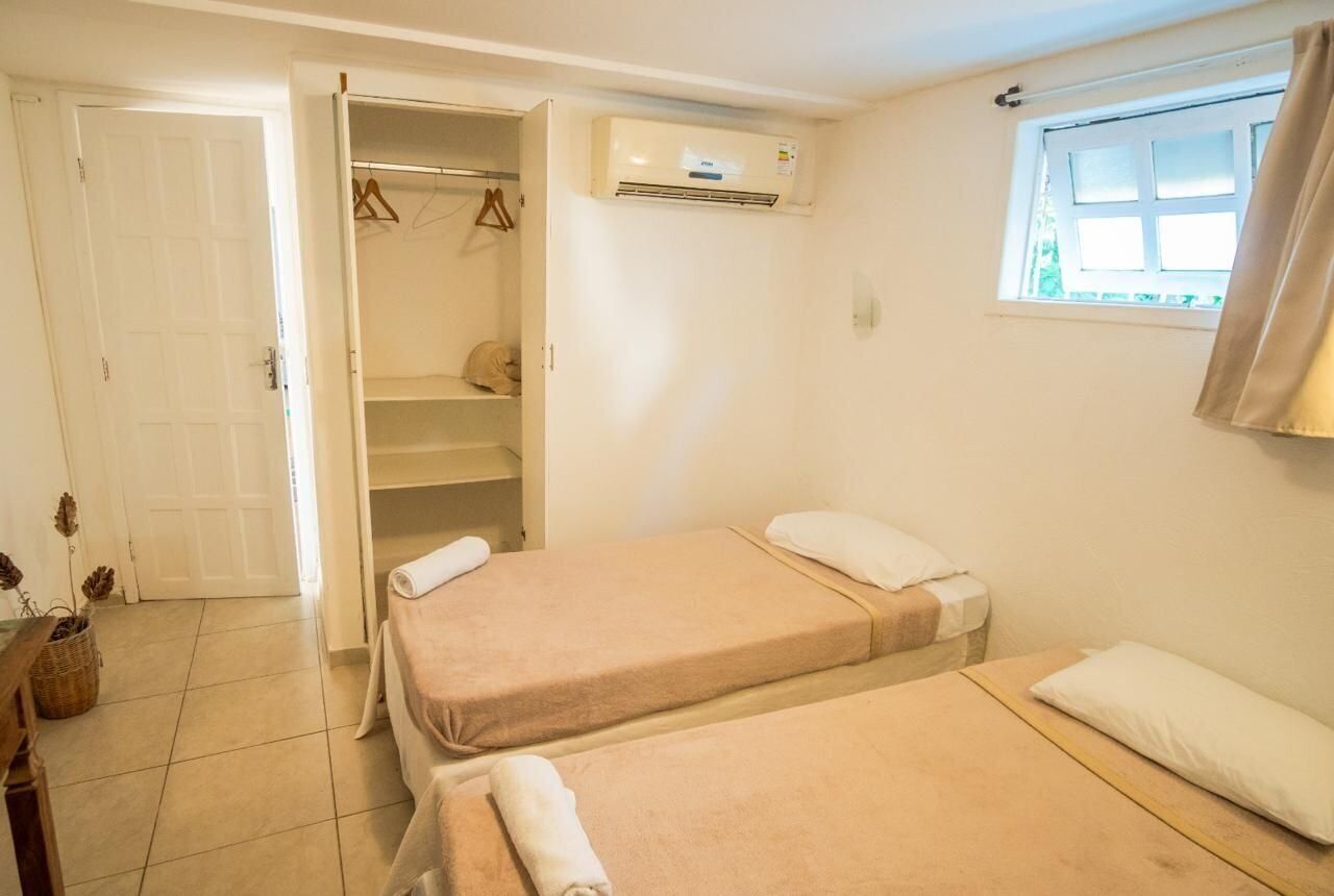 A room with two beds, a closet, and an air conditioning unit.