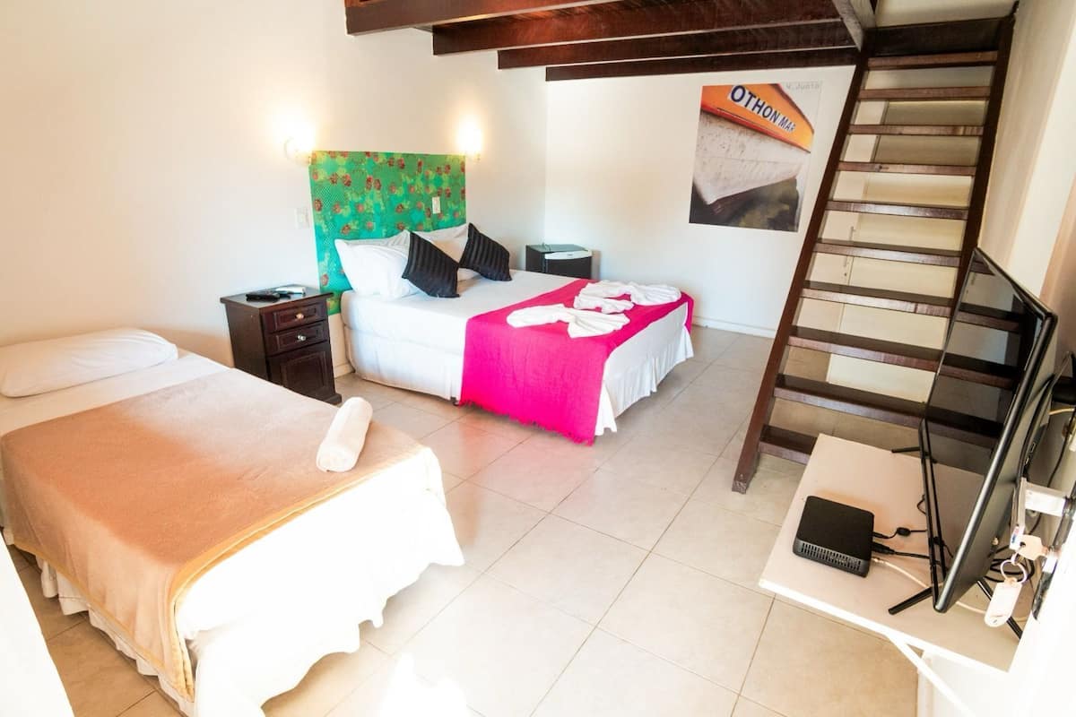 A hotel room with two beds, a desk, a chair, a laptop, a telephone, and a poster on the wall.