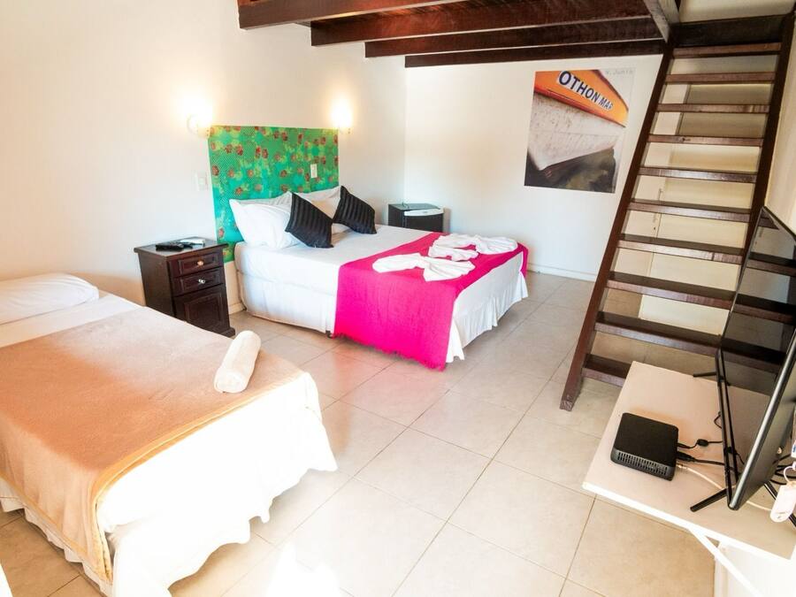A hotel room with two beds, a desk, a chair, a laptop, a telephone, and a poster on the wall.
