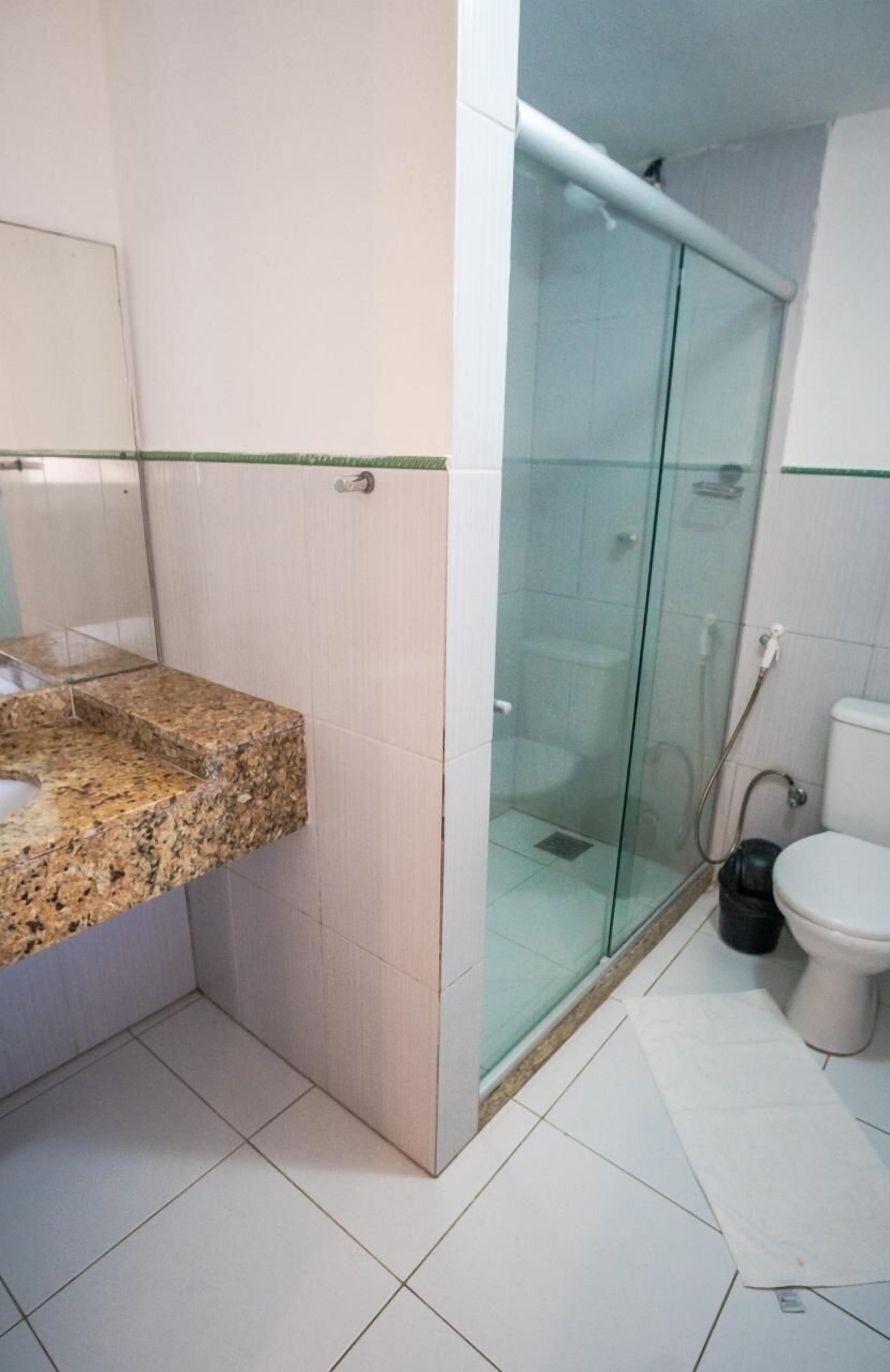 A bathroom with a granite countertop, a glass shower enclosure, and a white toilet.