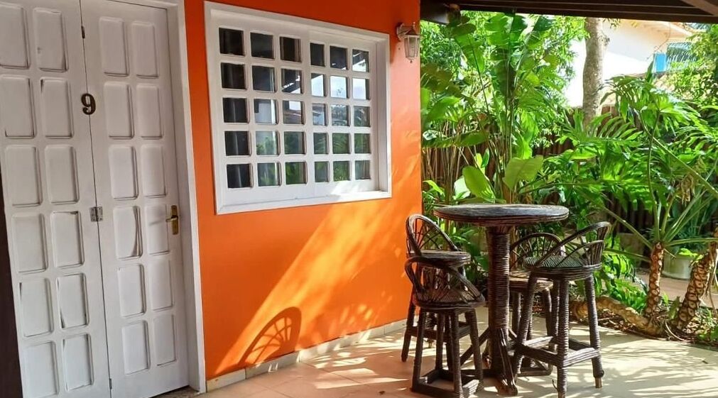 A room with a white door, a window with multiple panes, and a small round table with two chairs.