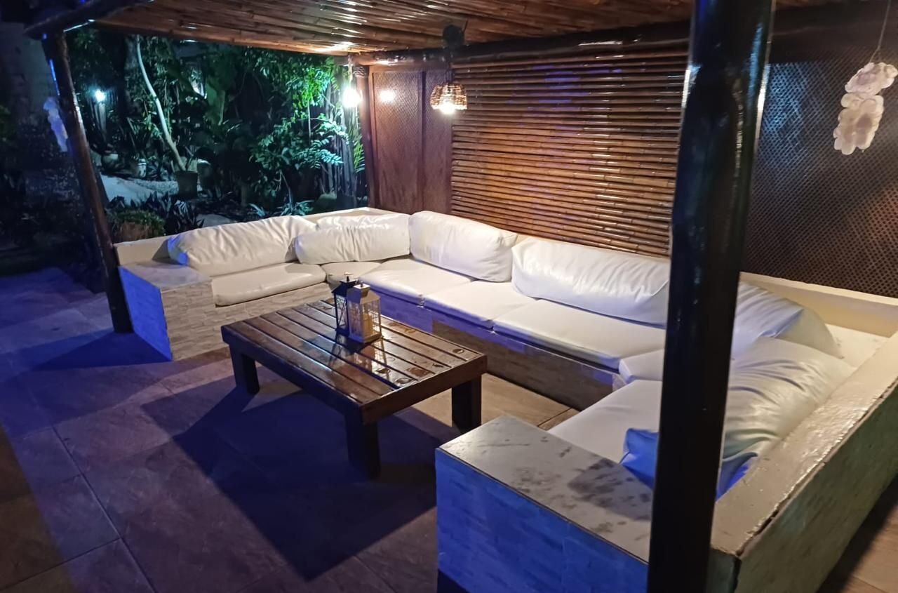 An outdoor seating area with a wooden bench, a cushioned sofa, and a small table.