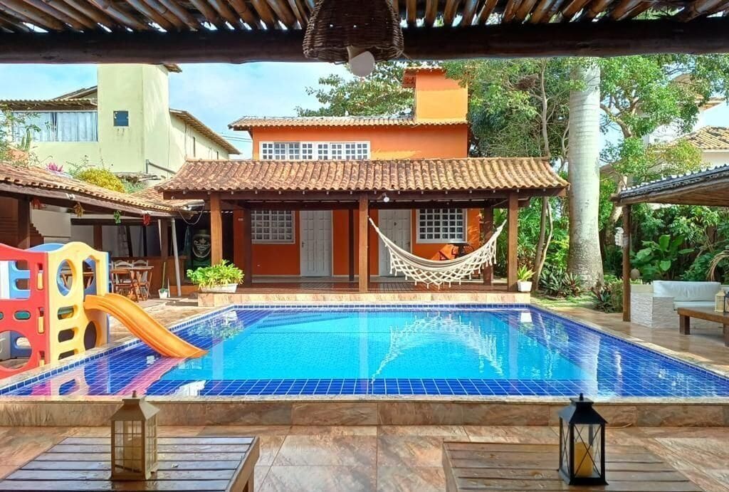 A swimming pool with a hammock, a slide, and a covered seating area.