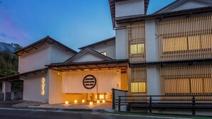 Un edificio japonés tradicional con una entrada moderna, un gran emblema y una serie de luces a lo largo del camino.